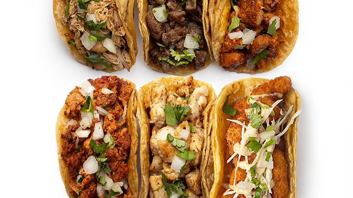 Office taco bar catering setup with tortillas, proteins, toppings, and sauces ready for a team lunch